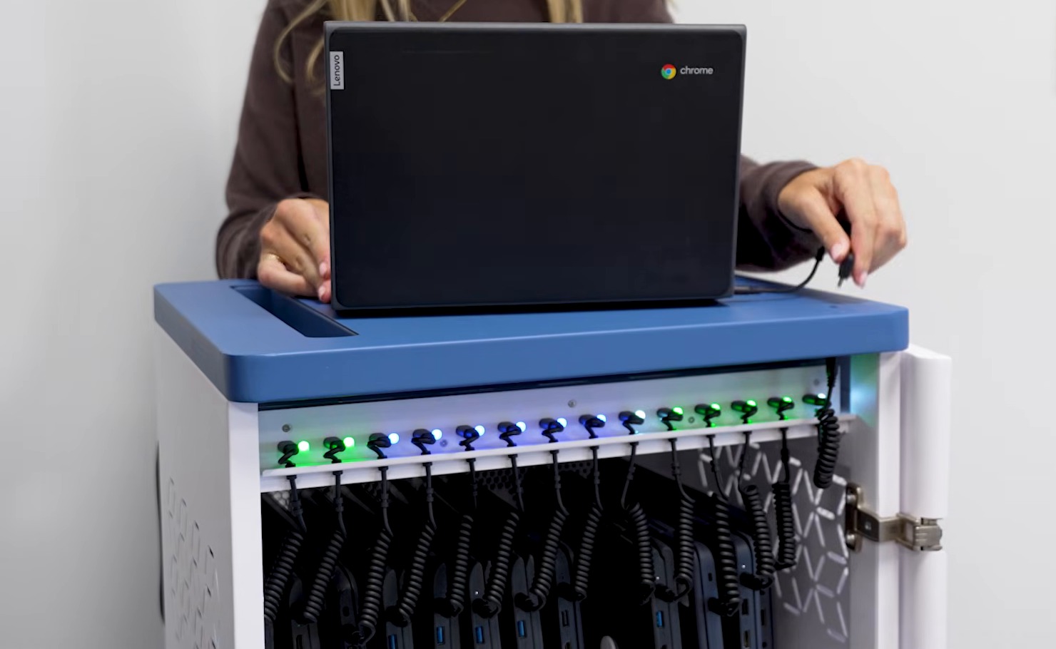 A Chromebook plugged in on top of an Elevate Evo 42, above its front-access charging hub with LED status lights and coiled cables