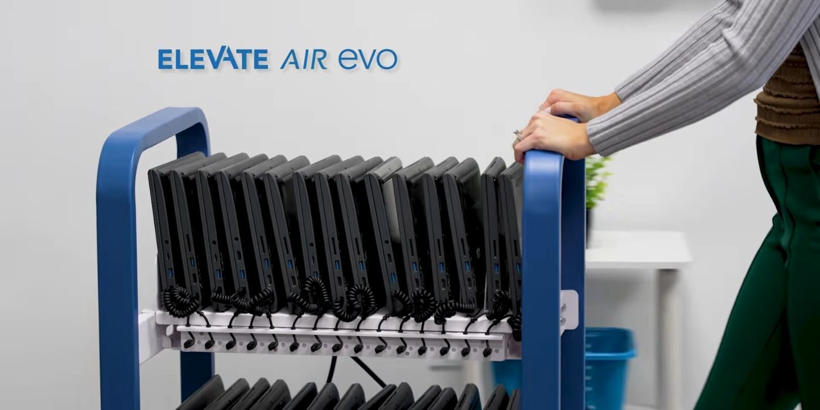 Person pushing the JAR Systems Elevate Air Evo open charging cart with two tiers of Chromebooks connected to USB-C charging cables.
