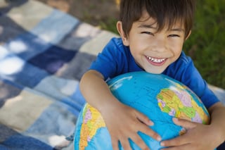 Close-up portrait of a cute young boy holding globe at the park.jpeg